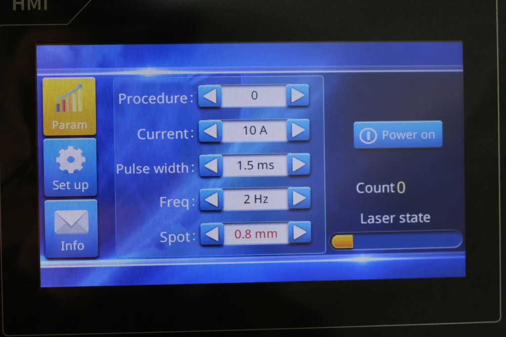 Close-up on the tactile parameter controls of a professional desktop welder, showing spot size and pulse settings for an alloy like platinum.